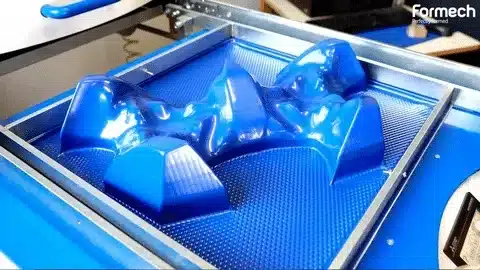 Close-up of a vacuum formed blue plastic piece with complex curves and surface details.