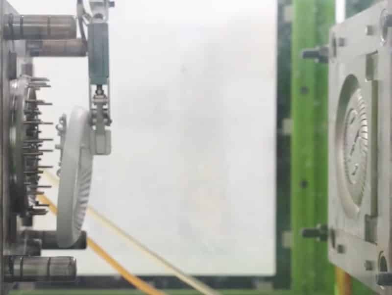 Close-up of injection molding machine closing mold with ejector pins and slide mechanisms visible