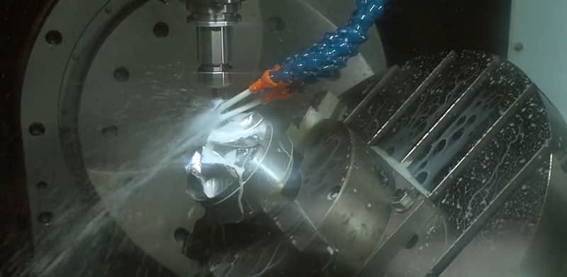  CNC machine tool in operation, cutting a precision mold component with coolant spray
