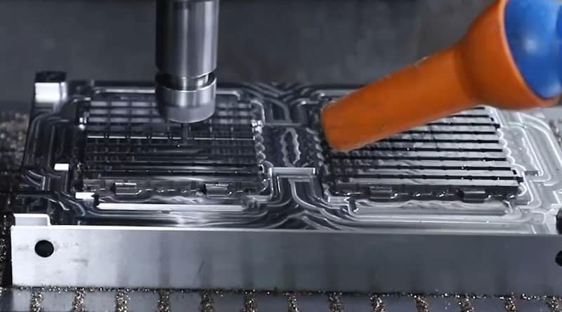 5-axis CNC machining of injection mold cavity with coolant spray and precision tooling for complex geometries