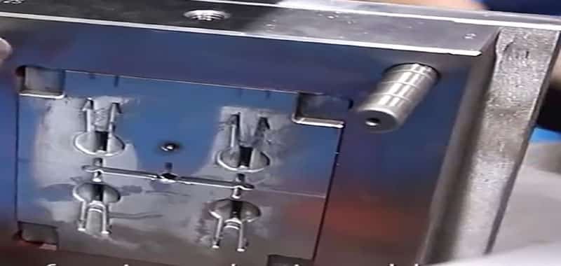 Side view of a mold's moving half showing slider mechanisms and ejector pins in place.