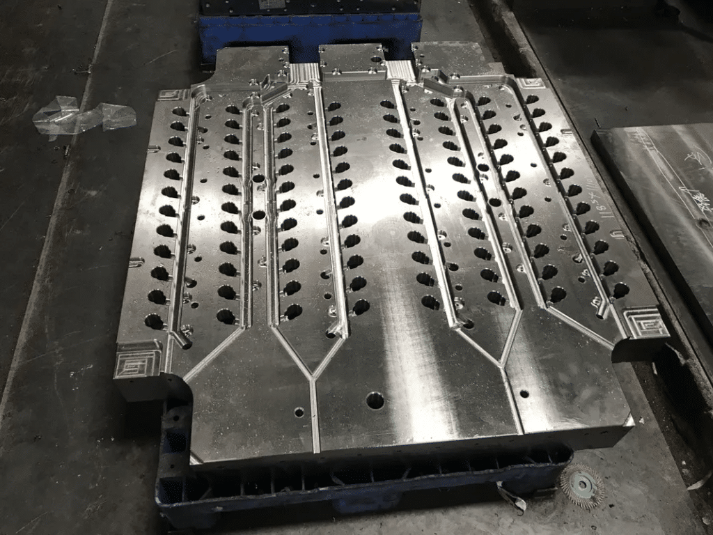 Large injection mold cavity plate manufactured from mold steel, showing precision CNC machining, cooling channels, and uniform hole layout for high-volume plastic injection molding